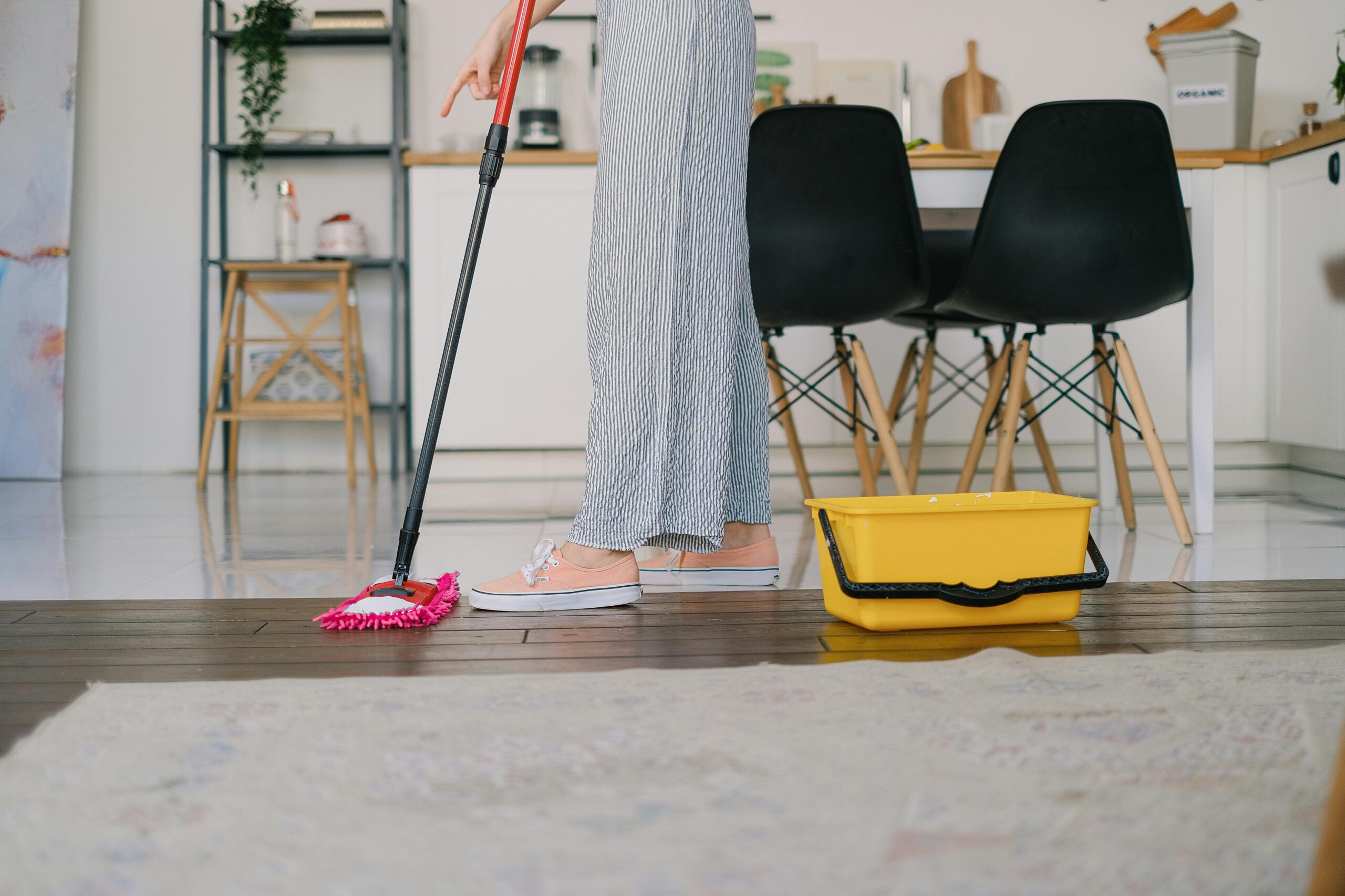 commercial-plumbing Side view of crop anonymous woman washing parquet with mop against bucket and carpet in house